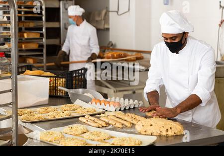 Boulanger masculin travaillant avec des baguettes formant de la pâte Banque D'Images