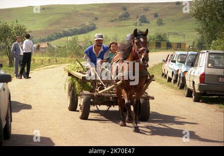 Comté de Brasov, Roumanie, 2001. Villageois dans un chariot tiré par des chevaux rempli de fourrage. Banque D'Images