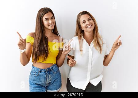 Mère et fille ensemble debout sur un arrière-plan isolé souriant confiant pointant avec les doigts vers différentes directions. copier l'espace pour Banque D'Images
