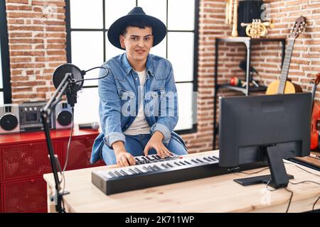 Jeune homme non binaire musicien jouant un clavier de piano dans un studio de musique Banque D'Images