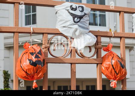 Têtes de citrouille artificielles d'un sac en plastique sur la clôture House en arrière-plan. Banque D'Images