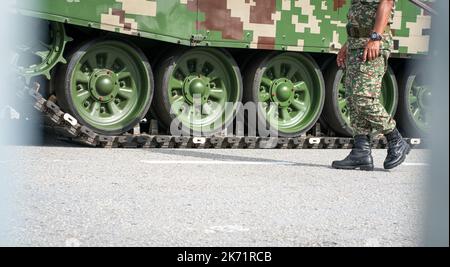 Jambes de soldat avec des bottes militaires et des pantalons de como, debout à côté d'un char en métal. Prise de vue à angle bas. Banque D'Images