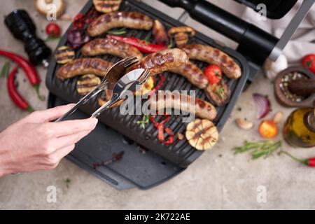 Saucisses et légumes grillés sur le gril électrique dans la cuisine Banque D'Images