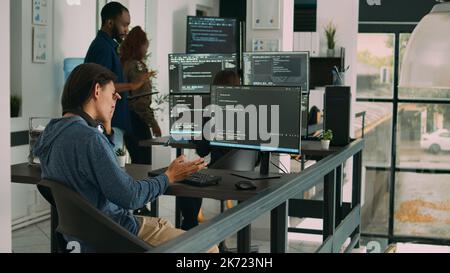 Programme logiciel en tapant le code source sur le clavier de l'ordinateur, en développant un serveur pare-feu et le cloud computing. Ingénieur INFORMATIQUE assis au bureau écrivant l'algorithme ai sur la fenêtre du terminal. Banque D'Images