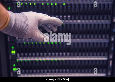 La main d'un ingénieur de sexe masculin sur un serveur de stockage de données, gros plan Banque D'Images