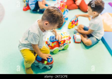 « mes voitures sont les plus cool » - les petits garçons jouant avec des jouets de voiture dans la pépinière. Photo de haute qualité Banque D'Images