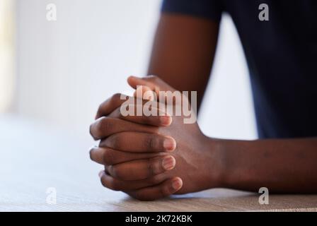 Il faut parler ici. Photo studio d'un homme méconnaissable assis à une table avec ses mains jointes. Banque D'Images