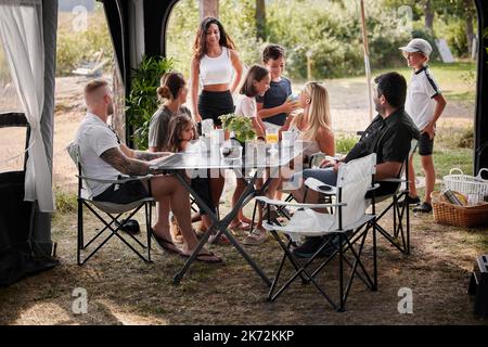 Amis avec des enfants se détendant sous le belvédère du jardin Banque D'Images