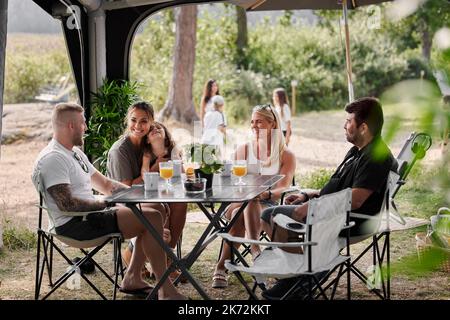 Amis avec des enfants se détendant sous le belvédère du jardin Banque D'Images