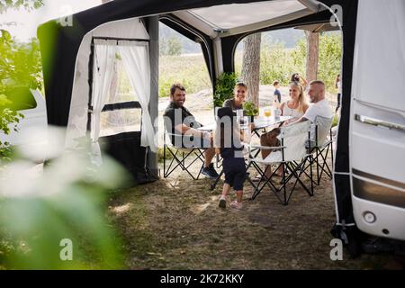 Amis avec des enfants se détendant sous le belvédère du jardin Banque D'Images