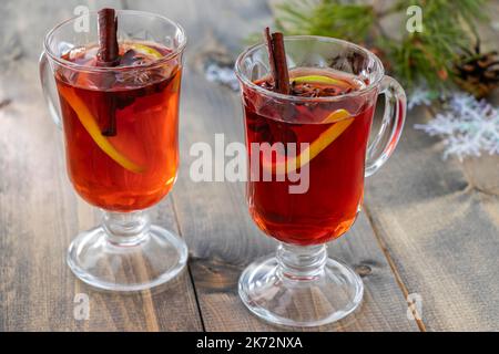 gros plan sur deux verres de punch épicé chaud avec bâtonnets de cannelle, anis étoilé et tranche d'orange sur une table en bois Banque D'Images