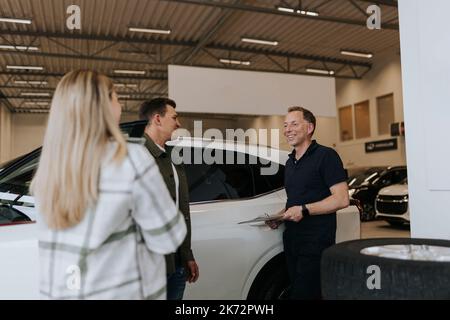 Vendeur parlant avec les clients de la concession automobile Banque D'Images