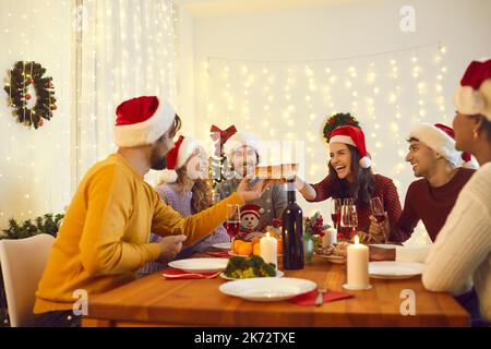 Des amis multiethniques souriants apprécient le dîner de Noël à la maison Banque D'Images