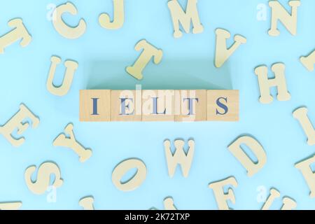 Examen ou concept de test IELTS ou international en anglais. Blocs de bois typographie à plat sur fond bleu. Banque D'Images