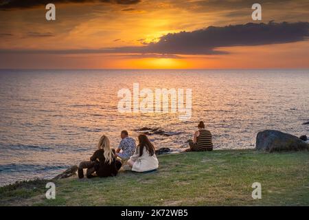 Vacanciers assis sur la côte et profitant d'un coucher de soleil spectaculaire sur la baie de Fistral à Newquay, en Cornouailles, au Royaume-Uni, en Europe. Banque D'Images