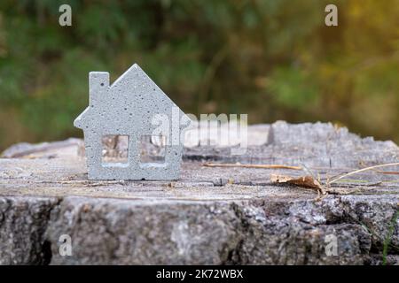 Modèle miniature de maison de jouets en béton sur une souche d'arbre, espace de copie. Concept de construction écologique et durable. Banque D'Images