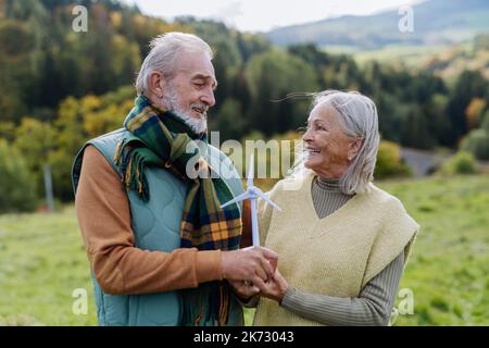 Couple senior tenant modèle plastique de l'éolienne dans la nature, concept de l'avenir, écologie et ressources renouvelables, message pour la prochaine génération Banque D'Images