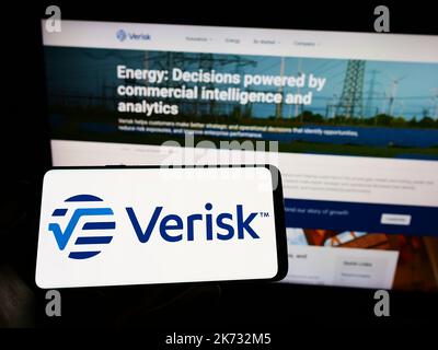 Personne tenant un téléphone portable avec le logo de la société américaine de données et de risque Verisk Analytics Inc. À l'écran devant la page Web. Mise au point sur l'affichage du téléphone. Banque D'Images