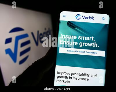 Personne tenant un téléphone portable avec la page Web de la société de données et de risque américaine Verisk Analytics Inc. À l'écran avec logo. Concentrez-vous sur le centre de l'écran du téléphone. Banque D'Images