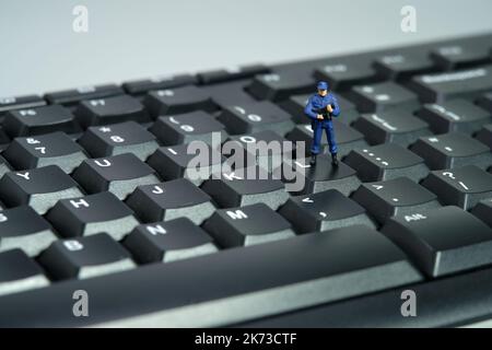 Photographie miniature de personnage de jouet de personnes. Concept de confidentialité de la saisie de données. Un agent de sécurité debout au-dessus du clavier. Isolé sur fond blanc. Image p Banque D'Images
