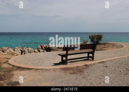 avec une vue directe sur la mer, un petit banc en bois se dresse sur une promenade de la plage et attend les randonneurs, l'espace copie Banque D'Images