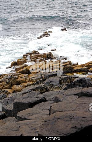 Vue sur les colonnes de basalte de Paléocène fracturées et érodées par les vagues qui se submergent dans la mer sur l'île de Staffa, dans les Hébrides intérieures, en Écosse. Banque D'Images