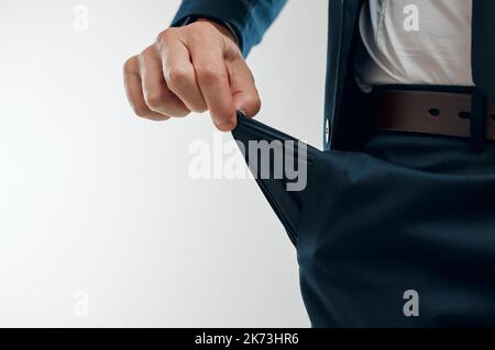 Complètement sans difficulté. Photo studio d'un homme d'affaires méconnu tirant une poche vide de son pantalon sur un fond blanc. Banque D'Images