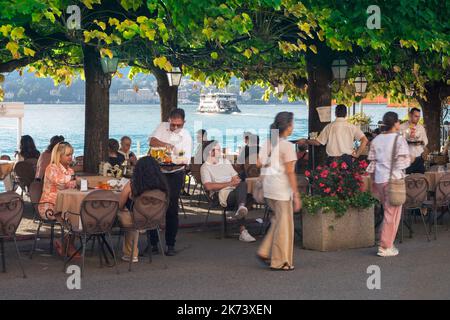 Restaurant Bellagio Italie, vue en été des personnes se détendant sur la terrasse d'un restaurant au bord du lac sur la Piazza Mazzini à Bellagio, Lac de Côme Banque D'Images