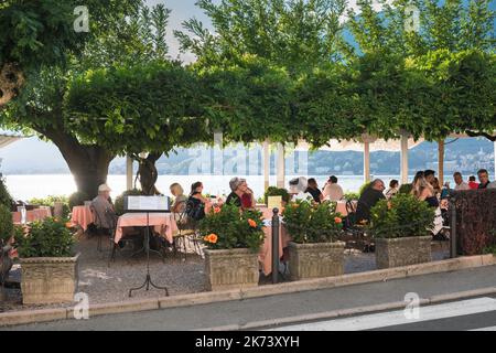 Restaurant Bellagio Italie, vue en été des personnes se détendant sur la terrasse d'un restaurant au bord du lac sur la Piazza Mazzini à Bellagio, Lac de Côme Banque D'Images