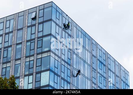 Deux hommes suspendus sur des cordes nettoyant les fenêtres d'une tour d'appartement, Londres, Royaume-Uni Banque D'Images
