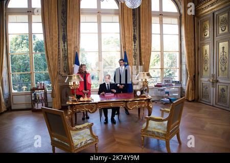 Le président français Emmanuel Macron (C), flanqué de la ministre de la Justice Nicole Belloubet et de la ministre déléguée aux relations avec le Parlement et porte-parole du gouvernement Christophe Castaner (R), signe des documents pour promulguer les projets de loi de foi dans la vie politique française sur 15 septembre 2017 dans son bureau à l'Elysée à Paris. Banque D'Images