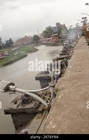 Ce temple est principalement utilisé pour la crémation extérieure des morts. Les corps sont transportés 24 heures après la mort jusqu'au temple, puis brûlés pendant 3 heures avant de voir des cendres jetées dans le fleuve Bagmati qui traverse le temple. Seuls les membres de la famille royale sont incinérés directement devant le temple de Pashupatinath. Banque D'Images