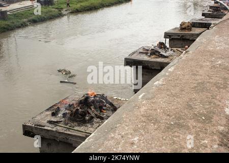 Ce temple est principalement utilisé pour la crémation extérieure des morts. Les corps sont transportés 24 heures après la mort jusqu'au temple, puis brûlés pendant 3 heures avant de voir des cendres jetées dans le fleuve Bagmati qui traverse le temple. Seuls les membres de la famille royale sont incinérés directement devant le temple de Pashupatinath. Banque D'Images