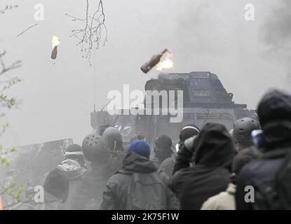 Les manifestants se protègent des gaz lacrymogènes sur la route D281 lorsqu'ils s'opposent à la police anti-émeute dans la ZAD (zone de défense a) à notre-Dame-des-Landes, dans l'ouest de la France, sur 9 avril 2018. Plus de 2 000 policiers français ont pris part à 10 avril à l'expulsion des derniers récalcitrants d'un camp anticapitaliste sur le site d'un projet d'aéroport abandonné près de la ville occidentale de Nantes. Les officiers ont essaié le site de notre-Dame-des-Landes avant l'aube pour expulser environ 100 des manifestants qui l'avaient occupé pour empêcher la construction d'un aéroport controversé, puis ont refusé de faire le vol Banque D'Images