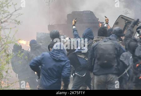 Les manifestants se protègent des gaz lacrymogènes sur la route D281 lorsqu'ils s'opposent à la police anti-émeute dans la ZAD (zone de défense a) à notre-Dame-des-Landes, dans l'ouest de la France, sur 9 avril 2018. Plus de 2 000 policiers français ont pris part à 10 avril à l'expulsion des derniers récalcitrants d'un camp anticapitaliste sur le site d'un projet d'aéroport abandonné près de la ville occidentale de Nantes. Les officiers ont essaié le site de notre-Dame-des-Landes avant l'aube pour expulser environ 100 des manifestants qui l'avaient occupé pour empêcher la construction d'un aéroport controversé, puis ont refusé de faire le vol Banque D'Images