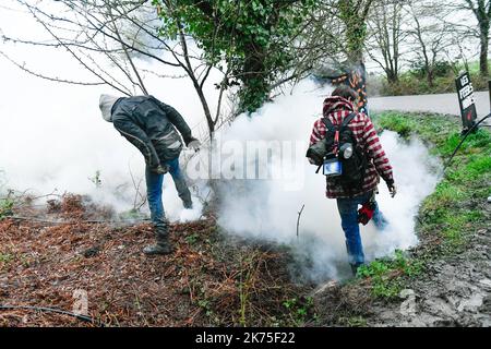 Les manifestants se protègent des gaz lacrymogènes sur la route D281 lorsqu'ils s'opposent à la police anti-émeute dans la ZAD (zone de défense a) à notre-Dame-des-Landes, dans l'ouest de la France, sur 9 avril 2018. Plus de 2 000 policiers français ont pris part à 10 avril à l'expulsion des derniers récalcitrants d'un camp anticapitaliste sur le site d'un projet d'aéroport abandonné près de la ville occidentale de Nantes. Les officiers ont essaié le site de notre-Dame-des-Landes avant l'aube pour expulser environ 100 des manifestants qui l'avaient occupé pour empêcher la construction d'un aéroport controversé, puis ont refusé de faire le vol Banque D'Images