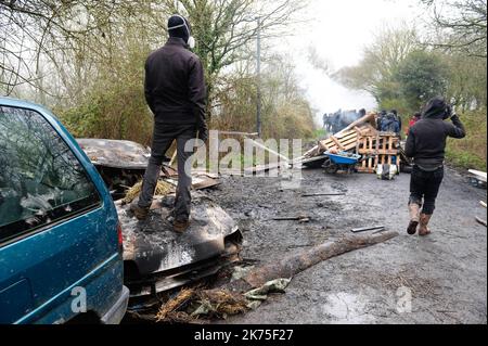 Les manifestants se protègent des gaz lacrymogènes sur la route D281 lorsqu'ils s'opposent à la police anti-émeute dans la ZAD (zone de défense a) à notre-Dame-des-Landes, dans l'ouest de la France, sur 9 avril 2018. Plus de 2 000 policiers français ont pris part à 10 avril à l'expulsion des derniers récalcitrants d'un camp anticapitaliste sur le site d'un projet d'aéroport abandonné près de la ville occidentale de Nantes. Les officiers ont essaié le site de notre-Dame-des-Landes avant l'aube pour expulser environ 100 des manifestants qui l'avaient occupé pour empêcher la construction d'un aéroport controversé, puis ont refusé de faire le vol Banque D'Images