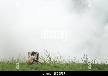 Les manifestants se protègent des gaz lacrymogènes sur la route D281 lorsqu'ils s'opposent à la police anti-émeute dans la ZAD (zone de défense a) à notre-Dame-des-Landes, dans l'ouest de la France, sur 9 avril 2018. Plus de 2 000 policiers français ont pris part à 10 avril à l'expulsion des derniers récalcitrants d'un camp anticapitaliste sur le site d'un projet d'aéroport abandonné près de la ville occidentale de Nantes. Les officiers ont essaié le site de notre-Dame-des-Landes avant l'aube pour expulser environ 100 des manifestants qui l'avaient occupé pour empêcher la construction d'un aéroport controversé, puis ont refusé de faire le vol Banque D'Images