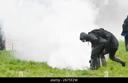 Les manifestants se protègent des gaz lacrymogènes sur la route D281 lorsqu'ils s'opposent à la police anti-émeute dans la ZAD (zone de défense a) à notre-Dame-des-Landes, dans l'ouest de la France, sur 9 avril 2018. Plus de 2 000 policiers français ont pris part à 10 avril à l'expulsion des derniers récalcitrants d'un camp anticapitaliste sur le site d'un projet d'aéroport abandonné près de la ville occidentale de Nantes. Les officiers ont essaié le site de notre-Dame-des-Landes avant l'aube pour expulser environ 100 des manifestants qui l'avaient occupé pour empêcher la construction d'un aéroport controversé, puis ont refusé de faire le vol Banque D'Images