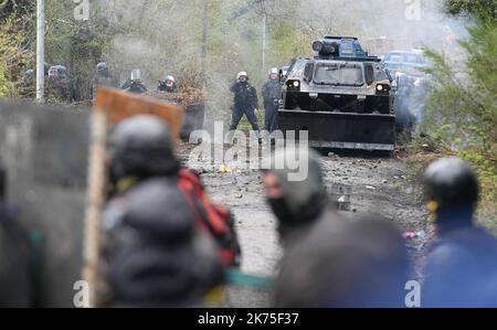 Les manifestants se protègent des gaz lacrymogènes sur la route D281 lorsqu'ils s'opposent à la police anti-émeute dans la ZAD (zone de défense a) à notre-Dame-des-Landes, dans l'ouest de la France, sur 9 avril 2018. Plus de 2 000 policiers français ont pris part à 10 avril à l'expulsion des derniers récalcitrants d'un camp anticapitaliste sur le site d'un projet d'aéroport abandonné près de la ville occidentale de Nantes. Les officiers ont essaié le site de notre-Dame-des-Landes avant l'aube pour expulser environ 100 des manifestants qui l'avaient occupé pour empêcher la construction d'un aéroport controversé, puis ont refusé de faire le vol Banque D'Images