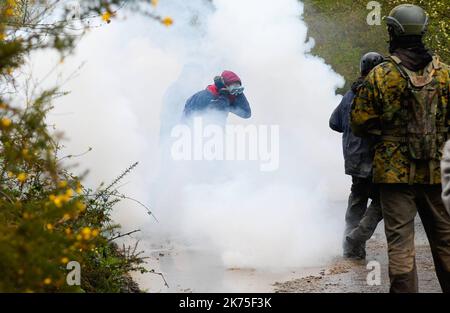 Les manifestants se protègent des gaz lacrymogènes sur la route D281 lorsqu'ils s'opposent à la police anti-émeute dans la ZAD (zone de défense a) à notre-Dame-des-Landes, dans l'ouest de la France, sur 9 avril 2018. Plus de 2 000 policiers français ont pris part à 10 avril à l'expulsion des derniers récalcitrants d'un camp anticapitaliste sur le site d'un projet d'aéroport abandonné près de la ville occidentale de Nantes. Les officiers ont essaié le site de notre-Dame-des-Landes avant l'aube pour expulser environ 100 des manifestants qui l'avaient occupé pour empêcher la construction d'un aéroport controversé, puis ont refusé de faire le vol Banque D'Images