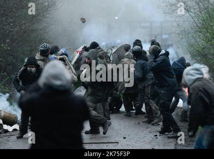 Les manifestants se protègent des gaz lacrymogènes sur la route D281 lorsqu'ils s'opposent à la police anti-émeute dans la ZAD (zone de défense a) à notre-Dame-des-Landes, dans l'ouest de la France, sur 9 avril 2018. Plus de 2 000 policiers français ont pris part à 10 avril à l'expulsion des derniers récalcitrants d'un camp anticapitaliste sur le site d'un projet d'aéroport abandonné près de la ville occidentale de Nantes. Les officiers ont essaié le site de notre-Dame-des-Landes avant l'aube pour expulser environ 100 des manifestants qui l'avaient occupé pour empêcher la construction d'un aéroport controversé, puis ont refusé de faire le vol Banque D'Images