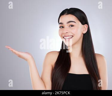 Mes meilleurs conseils pour une peau saine et éclatante. Studio portrait d'une jeune femme attrayante pointant vers le copyspace sur un fond gris. Banque D'Images