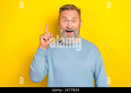 Photo de choqué impressionné retraité gars porter bleu chandail pointant le doigt vers le haut isolé couleur jaune arrière-plan Banque D'Images