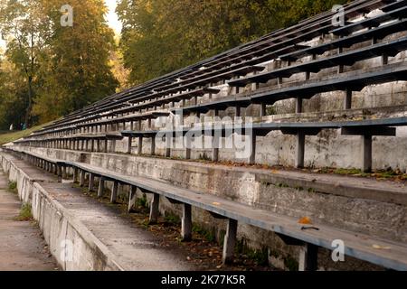 Vieux bancs d'oranches de la rue bleacher en automne doré. Places vides dans le stade sportif avec feuilles d'automne Banque D'Images