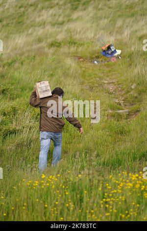 Clay Target Shooting - Sporting Welsh - homme transportant une boîte de cibles en haut d'une colline jusqu'à un piège Banque D'Images