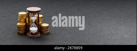 HourGlass devant des piles de pièces sur fond sombre Banque D'Images