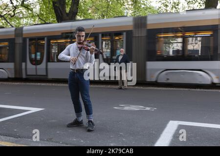 Belgique / Bruxelles / Bruxelles - Un jeune homme joue le violon dans la rue pour ses voisins dans des bâtiments et en soutien au personnel infirmier. Banque D'Images