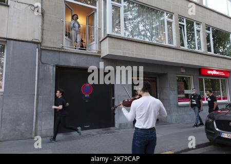 Belgique / Bruxelles / Bruxelles - Un jeune homme joue le violon dans la rue pour ses voisins dans des bâtiments et en soutien au personnel infirmier. Banque D'Images