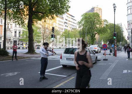 Belgique / Bruxelles / Bruxelles - Un jeune homme joue le violon dans la rue pour ses voisins dans des bâtiments et en soutien au personnel infirmier. Banque D'Images